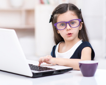Young girl wearing glasses using a laptop